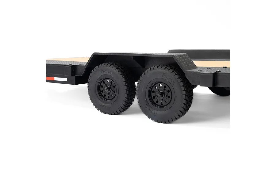 Close-up side view of the dual-axle wheels and black plastic fenders on an Axial 1/10 scale flatbed RC trailer.