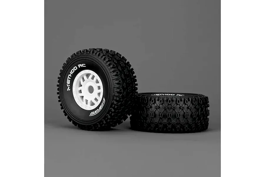 Two Method RC 2.3 Geoform all-terrain tyres mounted on white 12-spoke rims, shown against a grey background.
