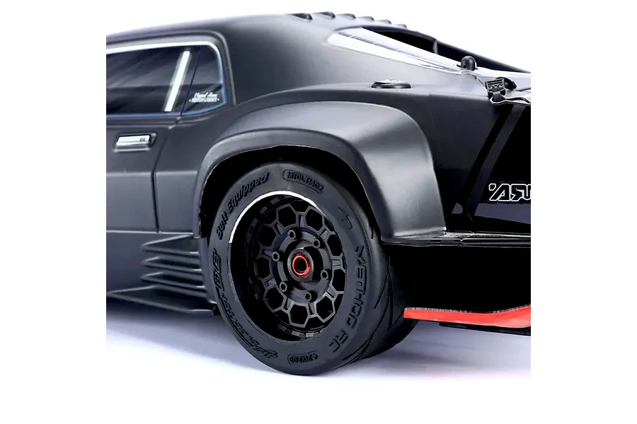 Close-up of a Method RC belted tyre and black hive rim mounted on the rear of a matte black RC car.