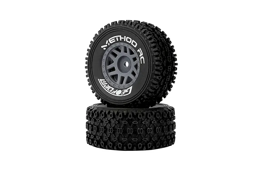 Two Method RC 1.2 Geoform all-terrain tyres mounted on grey 12-spoke rims, stacked vertically against a white background.
