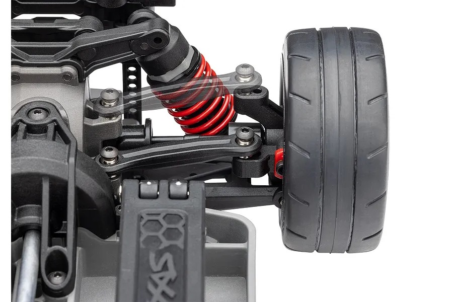 Close-up of the front suspension and wheel assembly of a Traxxas 4-Tec RC car, showing the red coil spring, black plastic control arms, and tire.