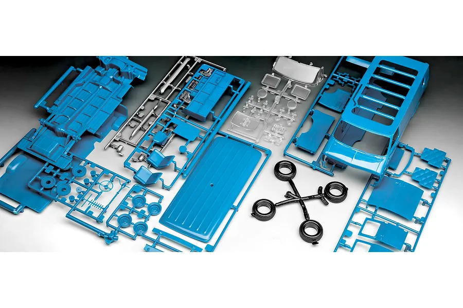 An overhead view of unpainted blue plastic model van parts on sprues, including a van body, interior panels, wheels, and clear plastic windows.