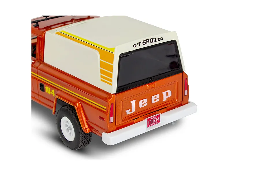 Rear three-quarter view of a 1/24 scale Revell Jeep J-10 pickup model kit with a white camper shell and orange body.