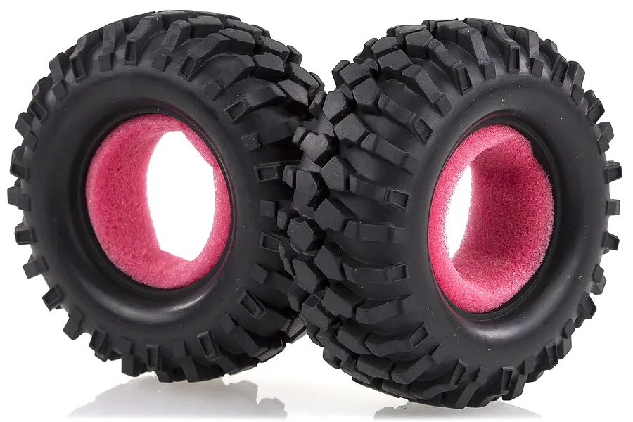 Two black rubber RC crawler tyres with aggressive tread patterns and bright pink foam inserts, isolated against a white background.
