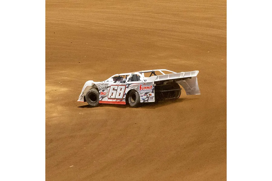 A white Losi 22S Dirt Late Model RC car with number 68 racing on a dirt track.