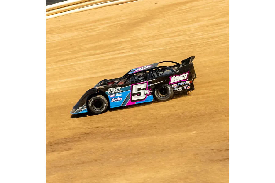 A Losi 22S Dirt Late Model RC car racing on a dirt track, featuring a black, blue, and pink livery with the number 5K on the side.