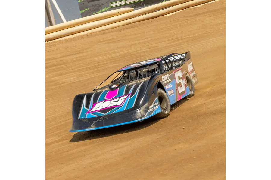 A Losi 22S Dirt Late Model RC car racing on a dirt track, featuring a black, blue, and pink livery with the number 5 on the side.