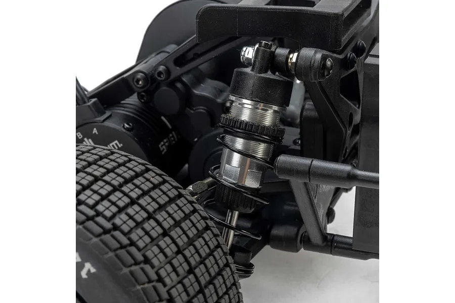 Close-up of the rear suspension and shock absorber on a Losi 22S RC car, showing the coil-over shock, tire tread, and chassis components.
