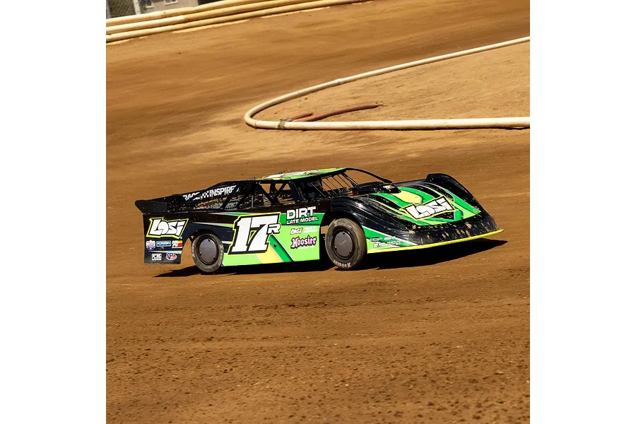 A green and black Losi 22S Dirt Late Model RC car racing on a dirt track.