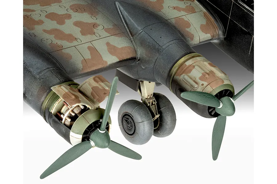 Close-up of a scale model aircraft wing showing two engines, propellers, and landing gear with camouflage paint.