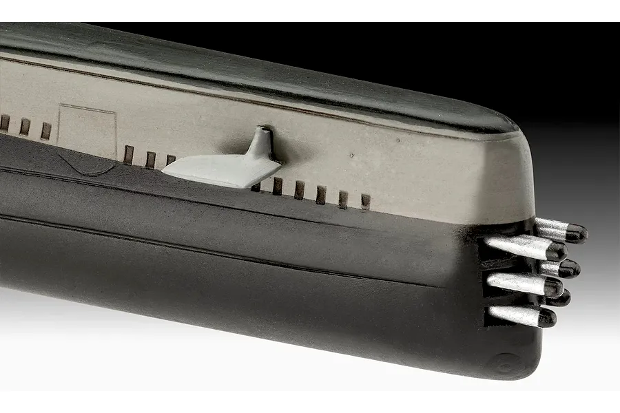 Close-up of the bow section of a plastic model submarine kit, showing the hull, a small fin, and torpedo tubes.