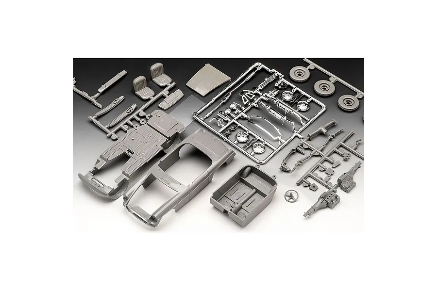 Unassembled plastic model car kit parts for a Revell 1/32 MGB Roadster, including grey sprues, a car body, interior tub, and chrome-plated parts.