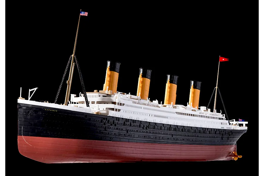 A finished plastic model of the RMS Titanic against a black background, showing the hull, funnels, and masts.