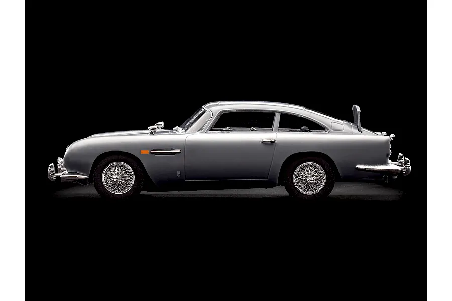 Side view of a silver Aston Martin DB5 model car on a black background.