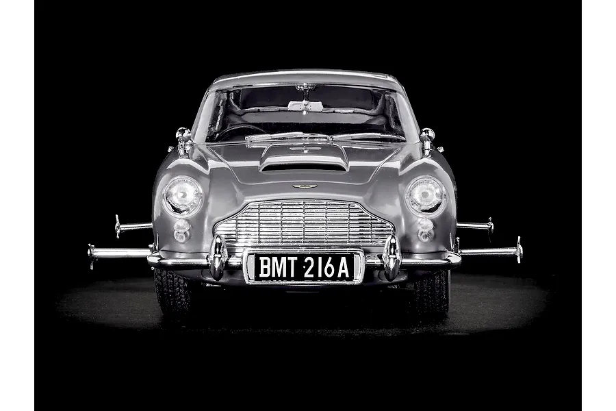 Front view of a silver Aston Martin DB5 model car with extended wheel spinners on a black background.