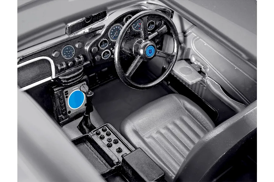 Close-up interior view of a 1/24 scale Aston Martin DB5 model kit showing the dashboard, steering wheel, and driver seat.