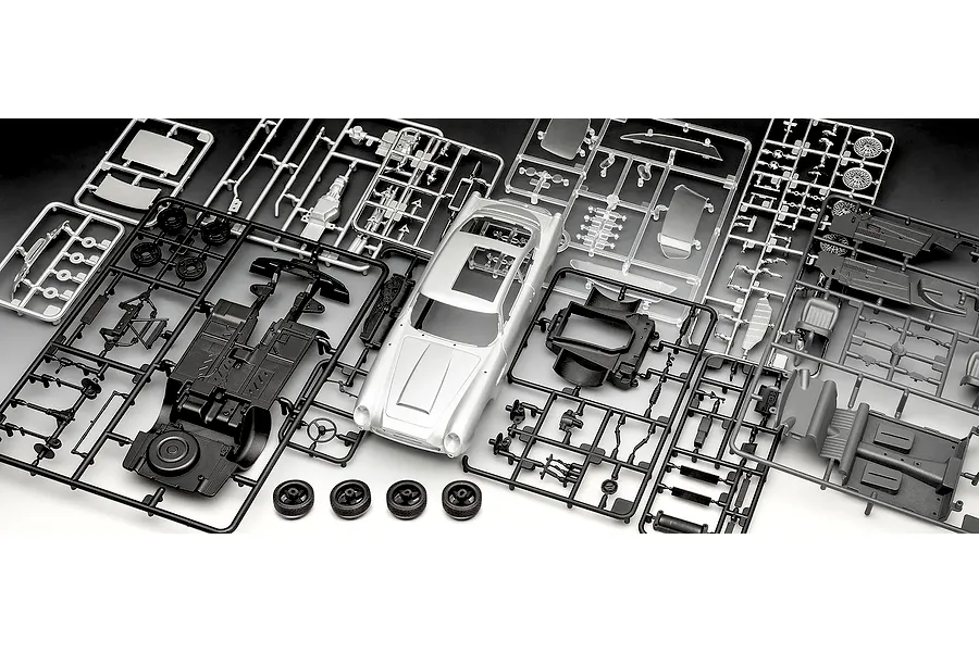 Plastic model kit parts for a 1/24 scale Aston Martin DB5, including a silver car body, black chassis, and various grey and chrome sprues.