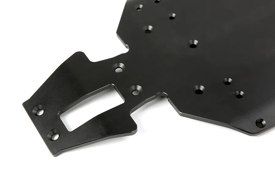 A close-up view of a black anodized aluminium RC car main chassis plate with various mounting holes and a rectangular cutout.