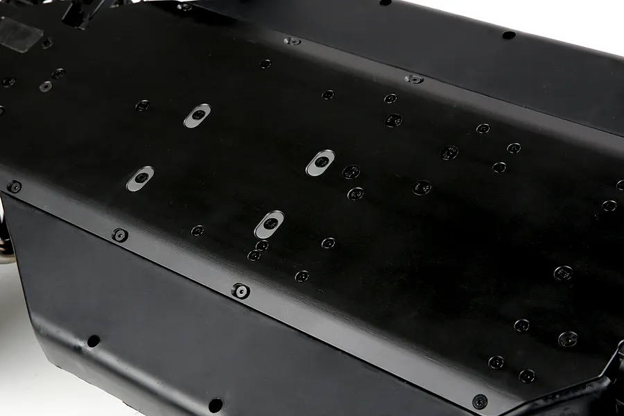 A close-up view of the black underside of a Rovan LT RC car main chassis, showing numerous screw holes and mounting points.