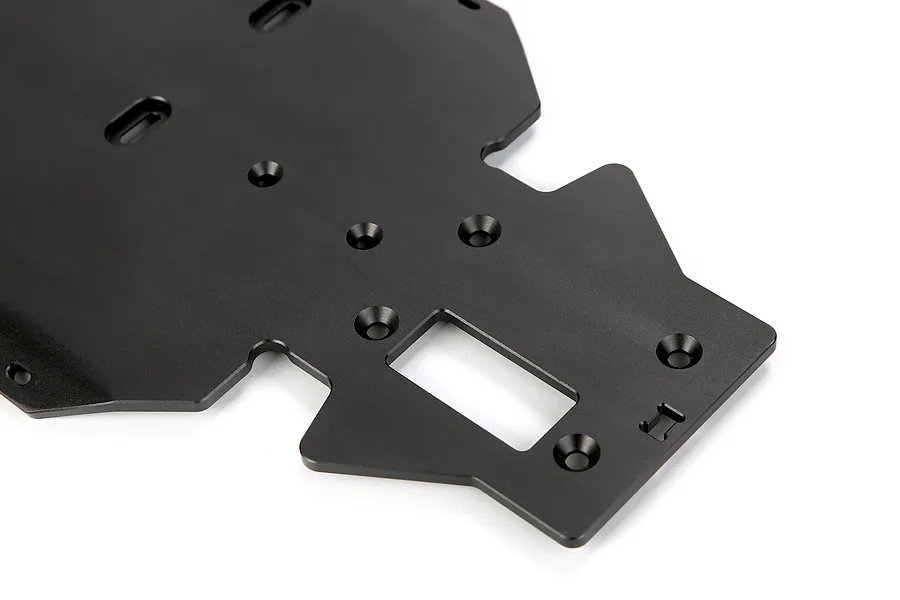 A close-up view of a black anodized aluminium RC main chassis plate featuring various mounting holes and a central rectangular cutout.