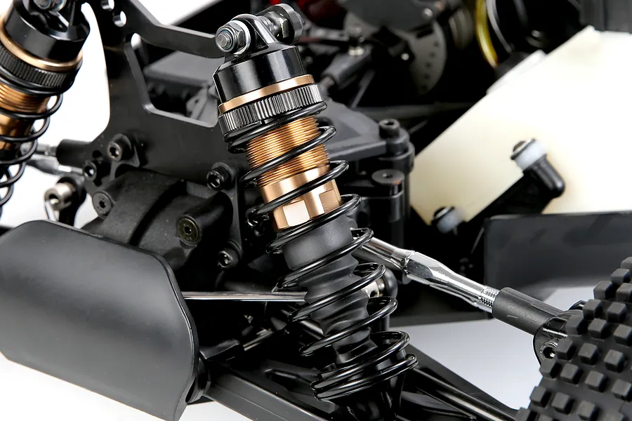 Close-up of bronze and black adjustable RC shock absorbers installed on a remote control vehicle chassis.