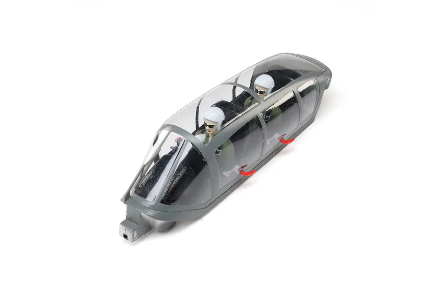 A grey E-Flite RC plane canopy hatch featuring a clear plastic windshield and two pilot figures with white helmets sitting inside.