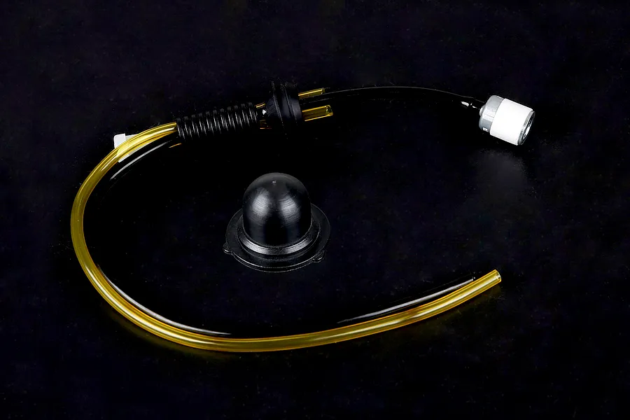 Rovan Baja fuel system kit including fuel tubing, a fuel filter, and a black rubber tank cap seal on a dark background.