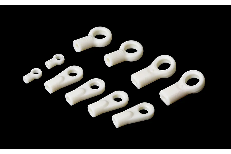 A set of various sizes of white plastic RC rod ends arranged on a black background.