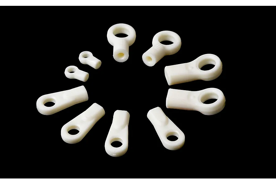 A collection of various white plastic RC ball ends arranged in a circle against a black background.