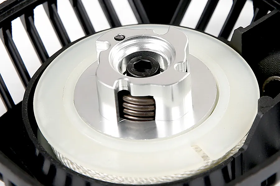Close-up of a Rovan pull start assembly showing the metal claw, white plastic spool, and black housing.