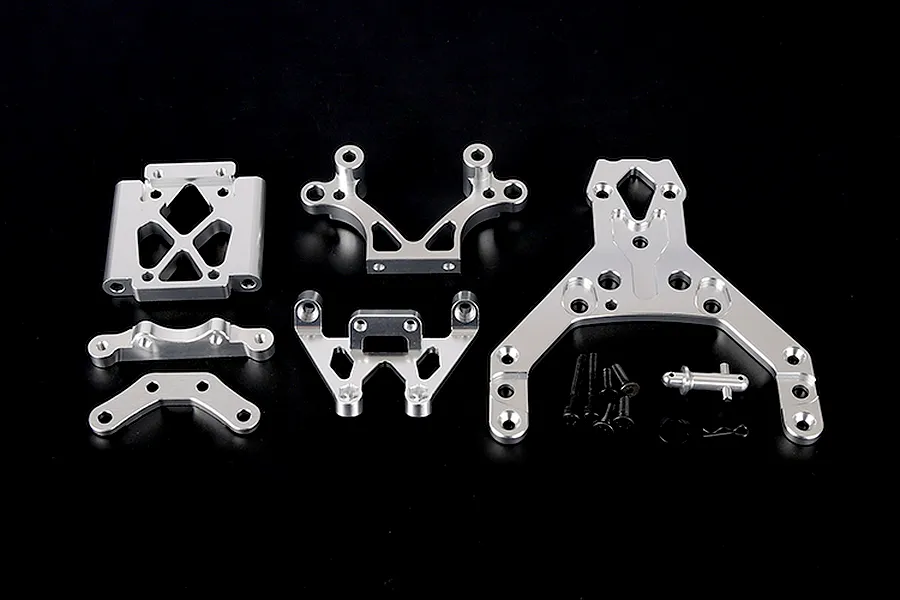 A set of silver aluminium RC front bulkhead components and an upper plate with mounting hardware on a black background.