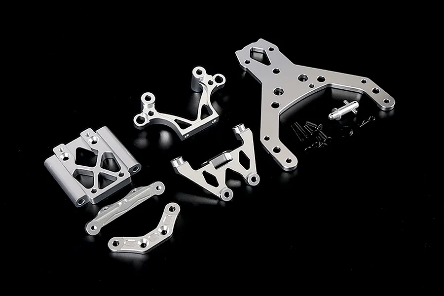 A set of silver aluminium RC front bulkhead components and an upper plate with mounting hardware on a black background.