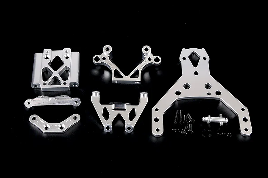 A set of silver aluminium RC car front bulkhead components, including plates, brackets, and mounting hardware, arranged on a black background.