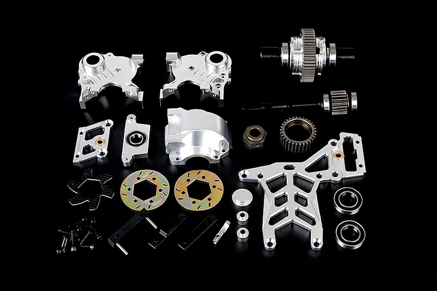 A collection of silver aluminium RC car transmission and differential parts laid out on a black background.