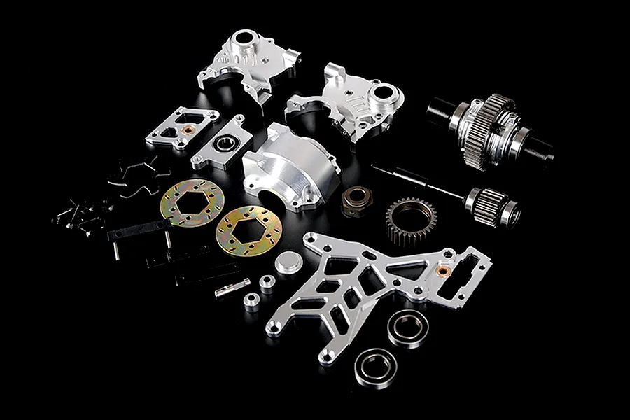 A collection of silver aluminium RC car differential and transmission parts laid out on a black surface.