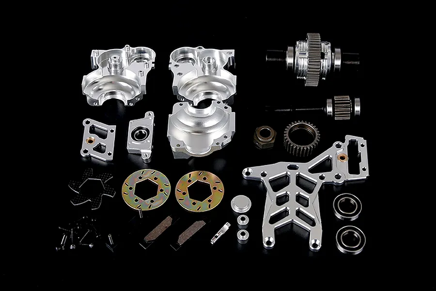 A collection of silver aluminium RC car transmission and differential parts laid out on a black background.
