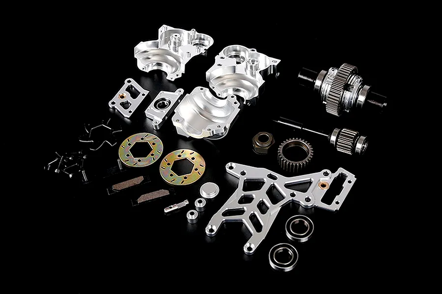 A collection of silver aluminium RC car differential and transmission parts laid out on a black background.