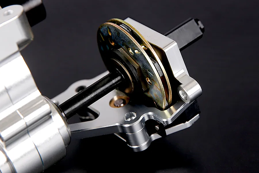 Close-up of a silver aluminium RC car transmission assembly with a brake disc mechanism on a black background.