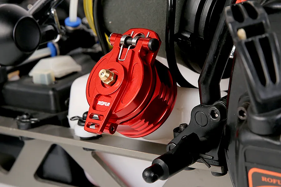A red anodized aluminium fuel tank cap with a spring-loaded latch installed on an RC car fuel tank.