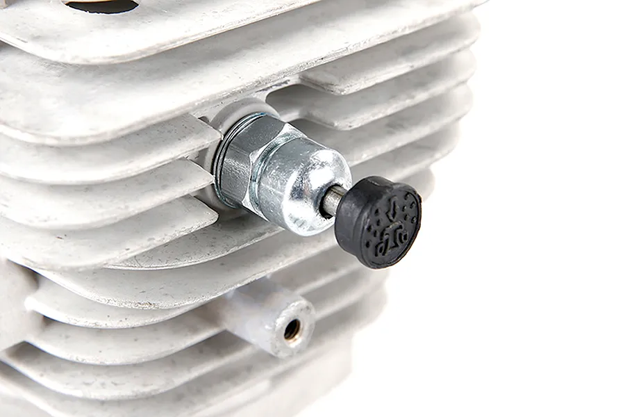 A close-up view of a pressure reducing valve installed on a finned metal RC engine cylinder head.