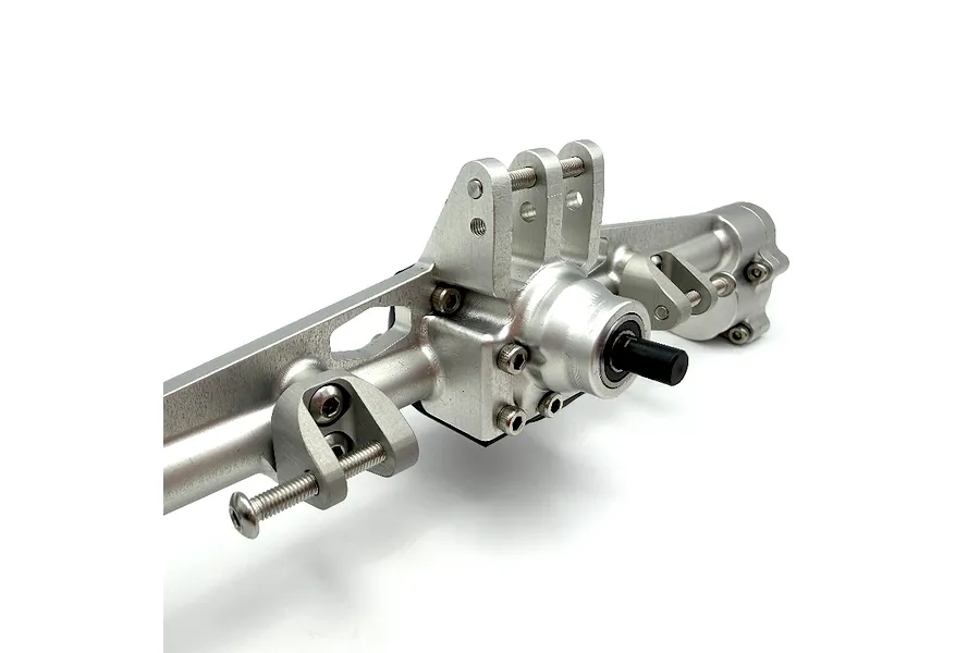 Silver aluminium RC rear axle housing with integrated link mounts and drive shaft input against a white background.