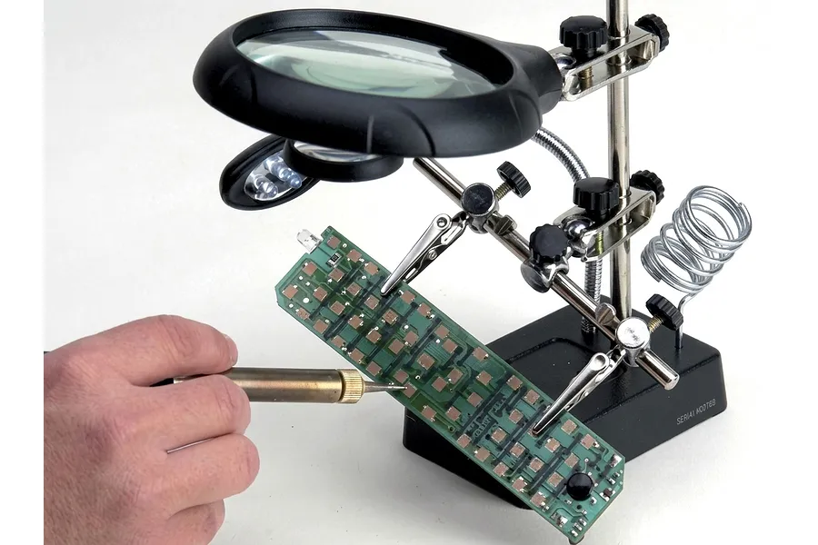 Artesania Latina third hand tool with magnifying glasses and LED lights being used to hold a circuit board while soldering.