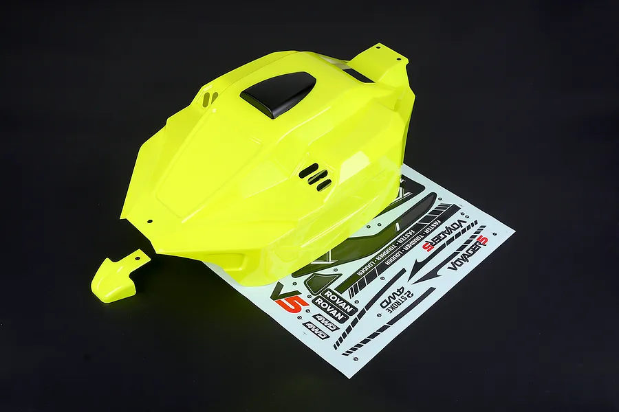 Bright yellow painted RC buggy body shell with a matching nose piece and a decal sheet on a dark background.