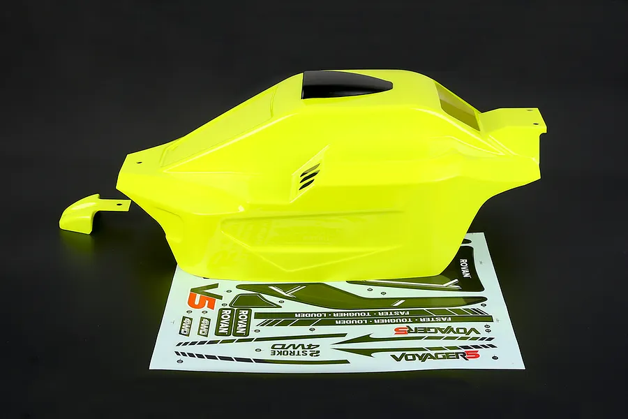 Bright yellow painted RC buggy body shell with a black roof scoop and accompanying sticker sheet on a dark background.