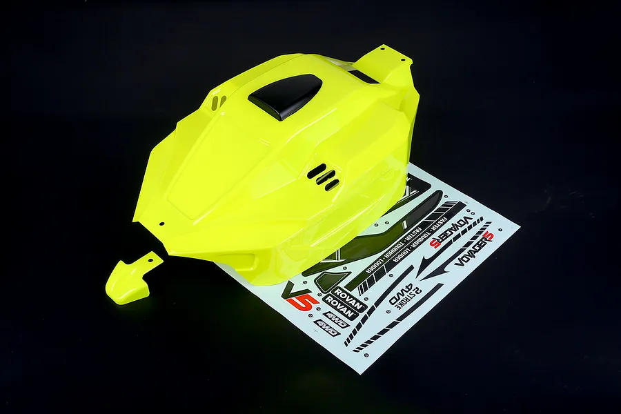 Bright yellow painted RC buggy body shell with a matching nose piece and a decal sheet on a dark background.