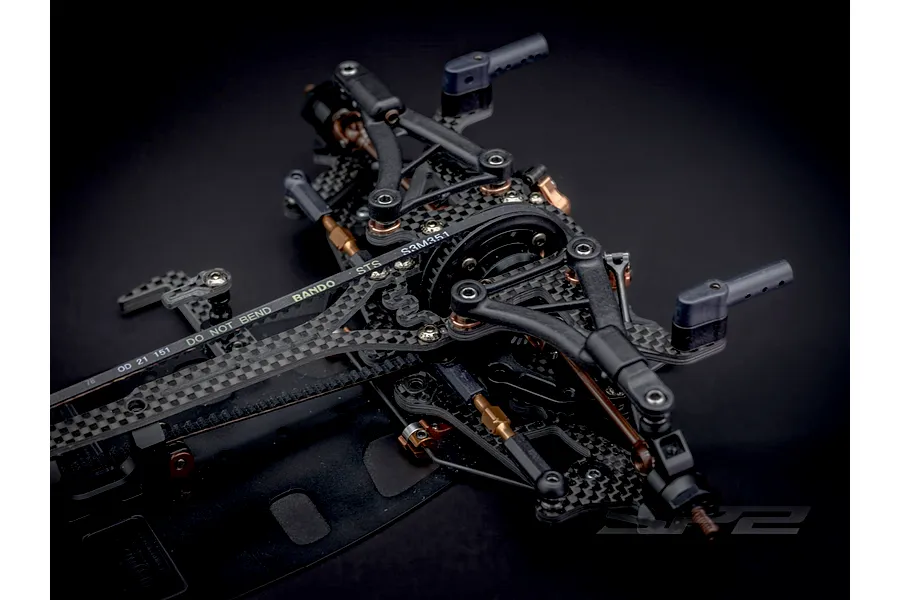Close-up studio view of the RC Maker SP2 EP RC touring car carbon fibre chassis and suspension components.