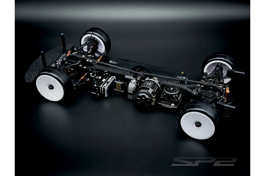 Studio shot of the RC Maker SP2 EP 1/10 electric touring car chassis assembled with electronics on a dark gradient background.