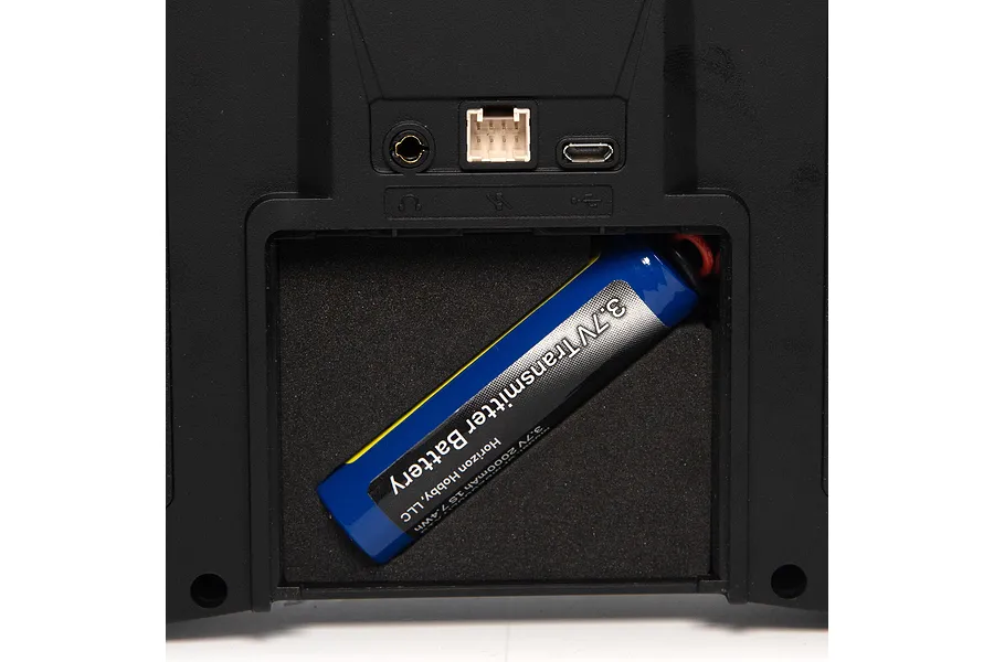 Close-up view of the battery compartment and port section on a Spektrum transmitter, showing a blue 3.7V battery installed inside.