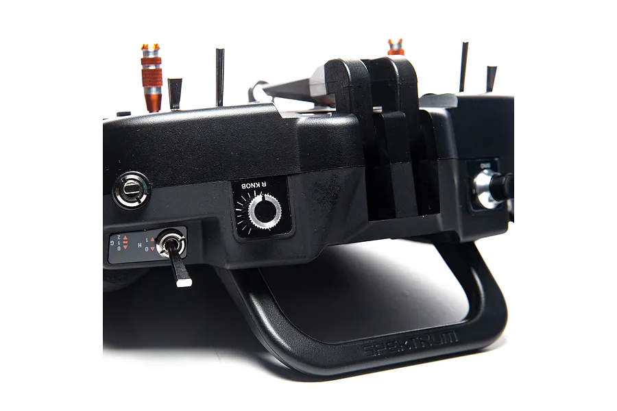 Close-up view of the top edge and handle of a black Spektrum radio transmitter, showing switches and control knobs.