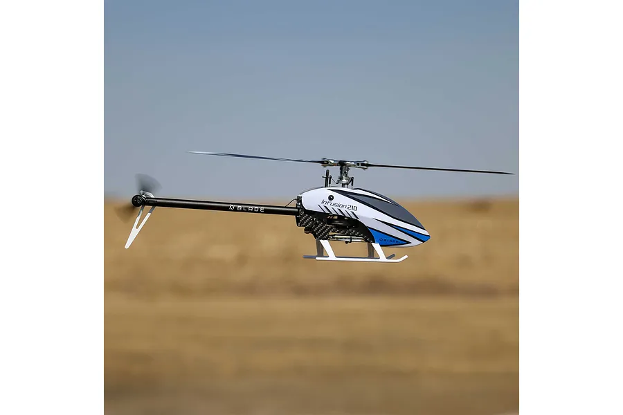 Blade InFusion 210 RC helicopter hovering outdoors in flight against a blurred background.